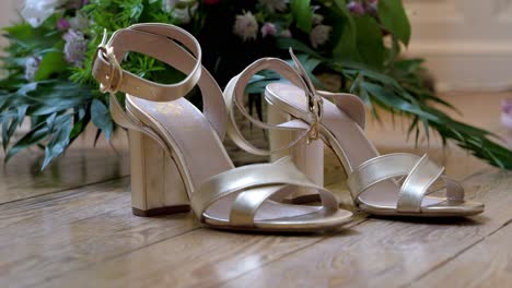 slow establishing shot of the brides wedding shoes infront of a bunch of flowers