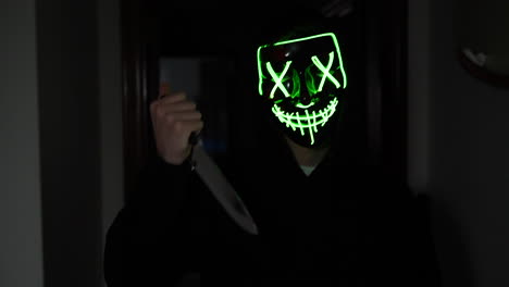 a terrifying killer in a generic halloween mask chasing a scared victim with a knife in slow motion