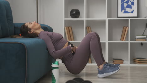 sporty young lady is doing exercise for abdominal with weight in living room training at self-isolation and lockdown at pandemic healthy lifestyle