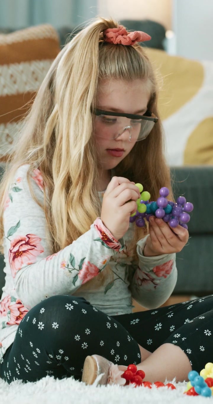 Ragazza con Occhiali di Sicurezza che Costruisce un Modello Molecolare