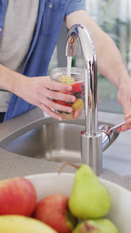 vertical video of hands of caucasian man washing fruits