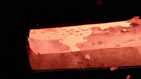 extreme closeup blacksmith forging red hot iron on anvil