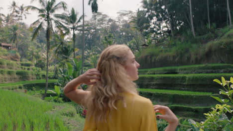 happy woman in rice paddy with arms raised celebrating travel freedom on exotic vacation looking at rice terrace sightseeing travel in bali indonesia