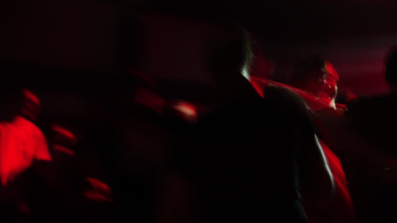 Blurred crowd of people dancing at a vibrant party with colorful lights and energetic atmosphere