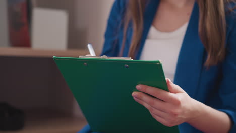 businesswoman plans week writing in notepad. serious lady student writes conspectus sitting in contemporary college class. woman writes text using clipboard