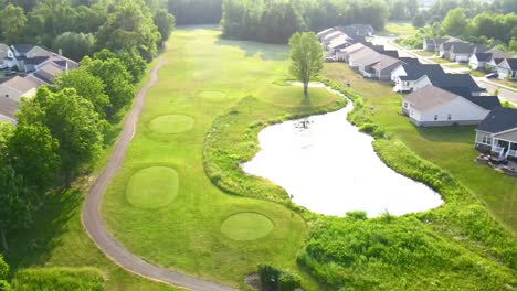 Drone-video-of-a-beautiful-hole-with-a-pond-on-a-golf-course-on-a-bright-sunny-day