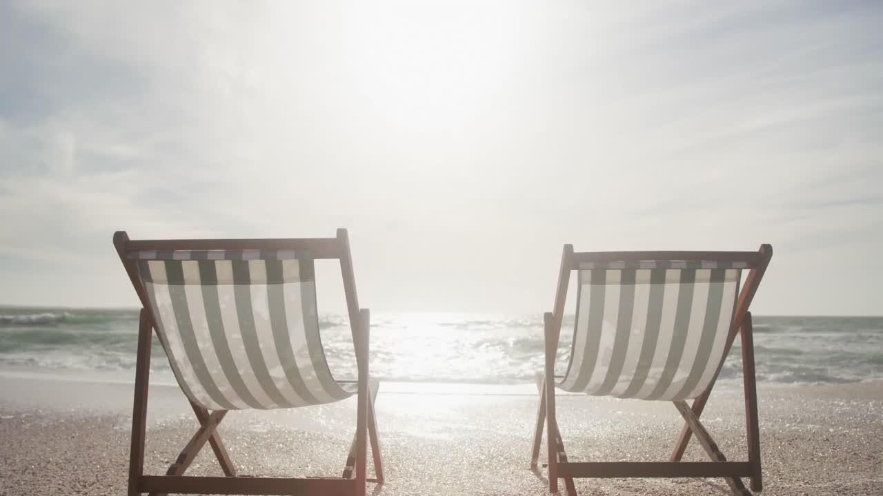 해가 지는 해변에 서 있는 두 개의 비어 있는  ⁇ 체어