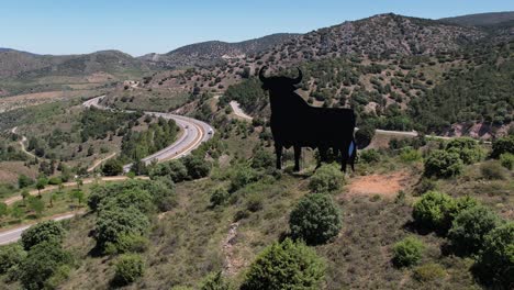 vista aérea de drones, vuelo circular alrededor del símbolo español el toro de osborne, icono nacional, en la cima de una colina