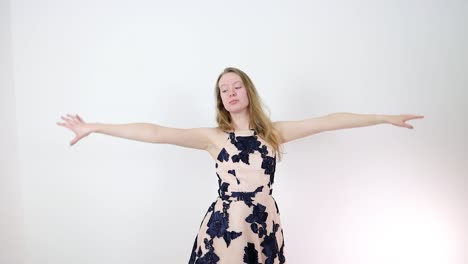 young woman in beige floral dress posing and dancing