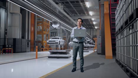 cuerpo lleno de un trabajador profesional masculino asiático de pie con su computadora portátil en la fábrica de automóviles ev, instalación industrial de alta tecnología, observa mirando a su alrededor antes de concentrarse con su portátil