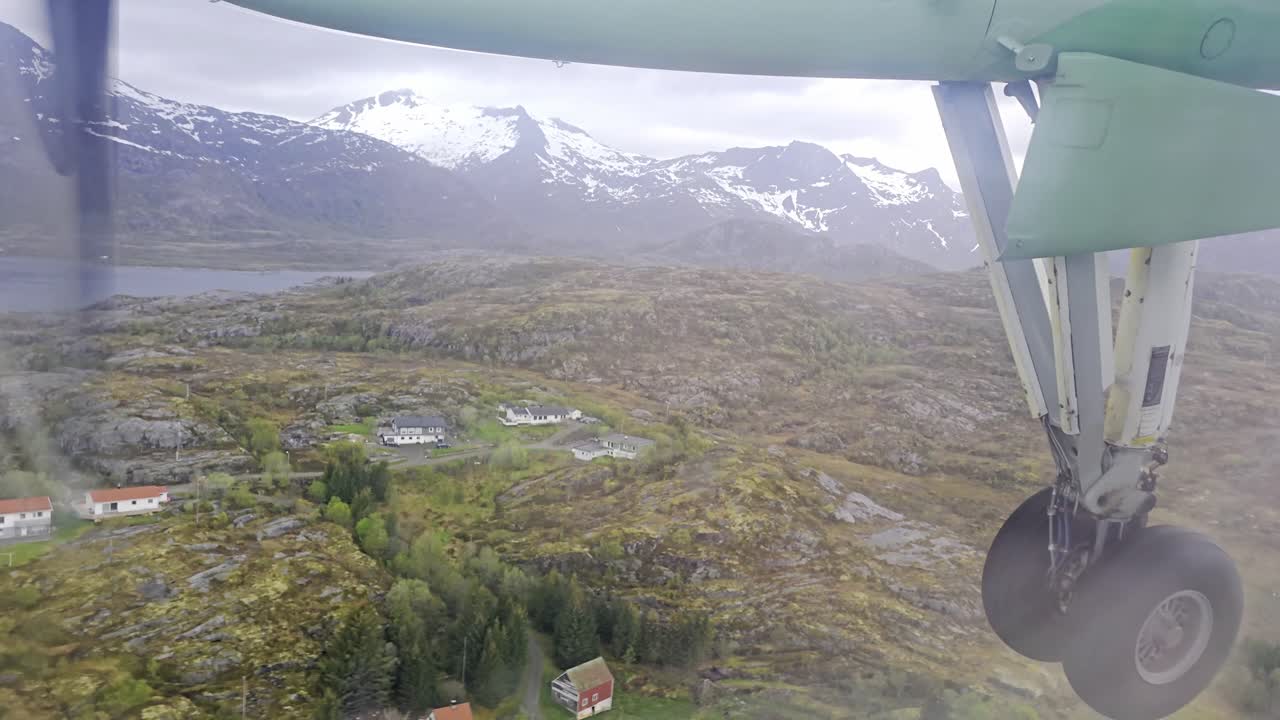 Handheld window view of Wideroe turboprop with gear down during spring approach to Svolvaer airport