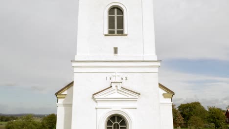 moving upwards alongside white church facade with tower and cross