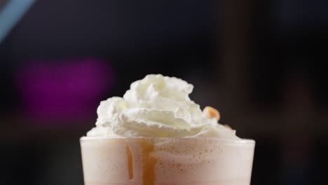 dropping caramel pieces over whipped cream side view milkshake