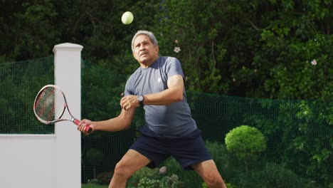 video enfocado de un hombre mayor biracial jugando al tenis en una cancha de tenis