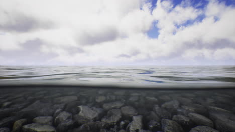 view of tranquil water surface with clouds reflecting above and stones below