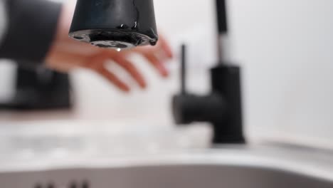 Person-Closing-Black-Color-Luxurious-Faucet,-Water-Drops