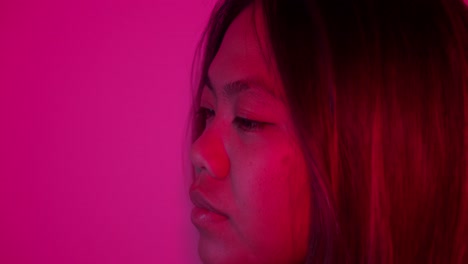 close-up portrait of a young asian woman with pink lighting