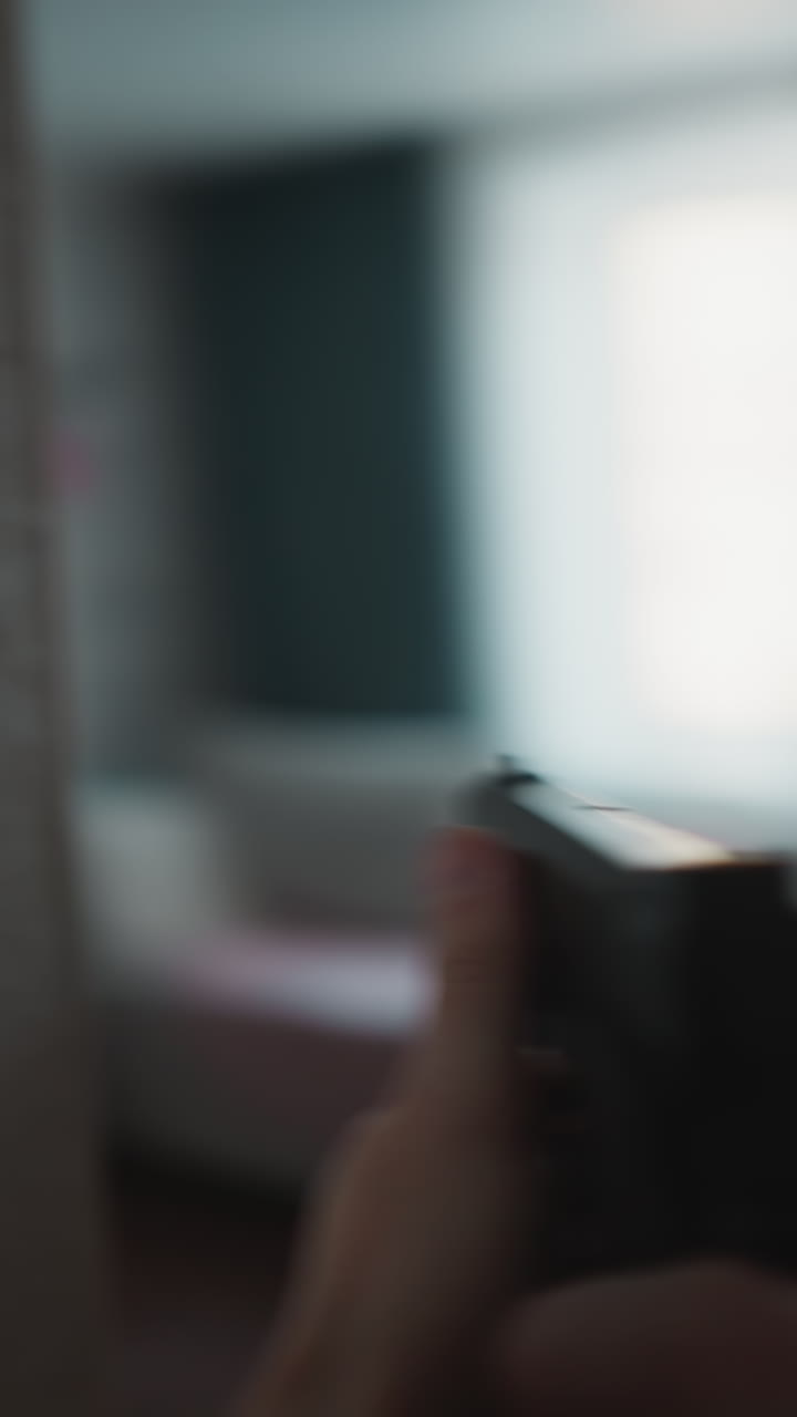 Armed first-person POV: a vigilant individual walks through rooms, handgun ready and aimed, surveying with caution