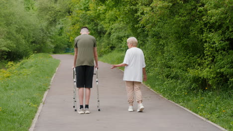 teenager with walker being assisted by an elderly woman in a park