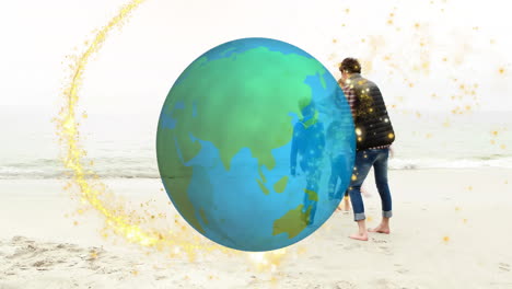 earth animation over person walking on beach with colorful sparkles