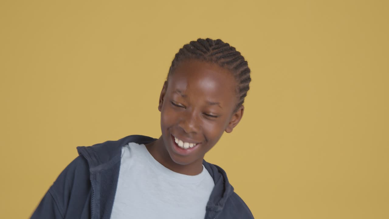 Portrait en studio d'un jeune garçon souriant et riant sur fond jaune 1