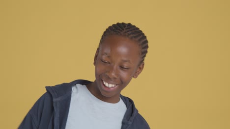 Studio-Portrait-Of-Young-Boy-Smiling-And-Laughing-Against-Yellow-Background-1