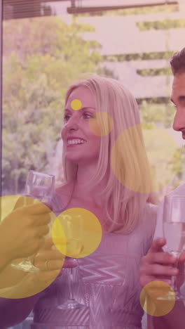 animation of yellow dots over happy caucasian female and male friends drinking wine and talking