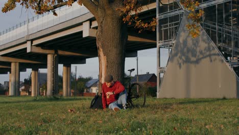 man with a bike under an overpass in autumn