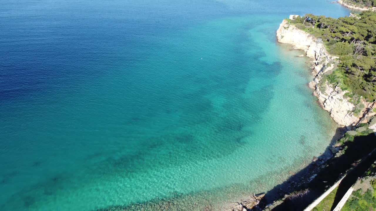 Vista aerea in allontanamento su una piccola isola e un castello circondati da acqua turchese nella Baia di Souda, Creta, Grecia.