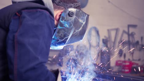 person with special safety equipment welding a metal joint in slow motion in workshop