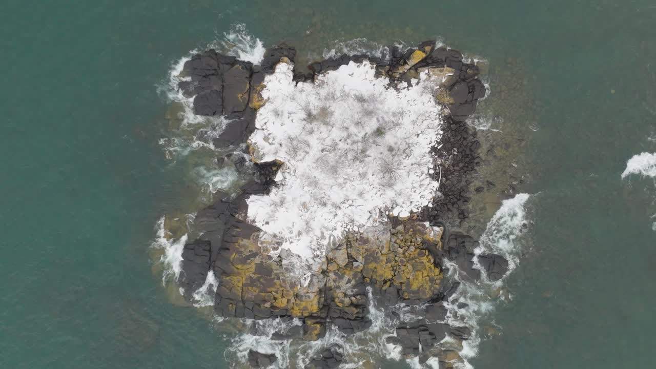 Overhead View Of Rocky Islet In The Lake With Snow In Winter. - aerial shot