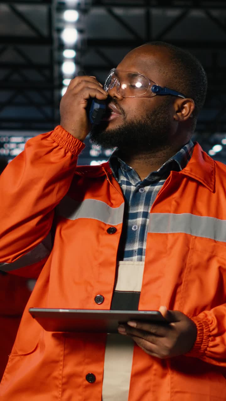 Vertical Video Factory worker communicates through walkie talkie near automation machinery