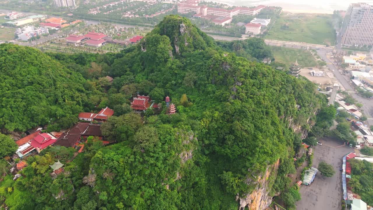 drone fly close to Marble Mountain in Da Nang city in Vietnam with ocean beach and city in the background aerial view of buddhist temple and pagoda