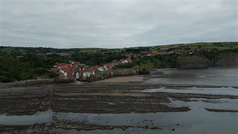 rising establishing drone shot of robin hood's bay at low tide on overcast morning