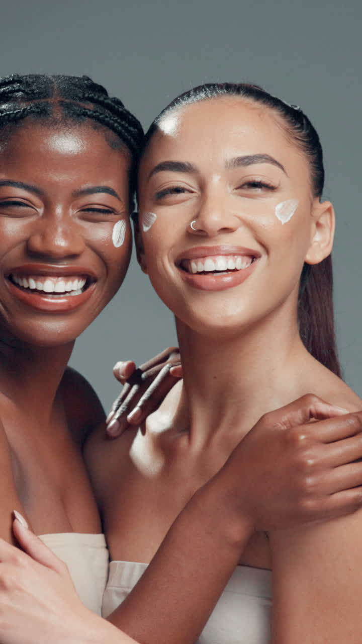 Duas mulheres diversas sorrindo e rindo com creme no rosto