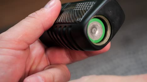 a man inserts a green battery into an e-cigarette