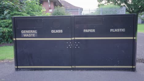 four black metal disposal containers for waste, glass, paper and plastic