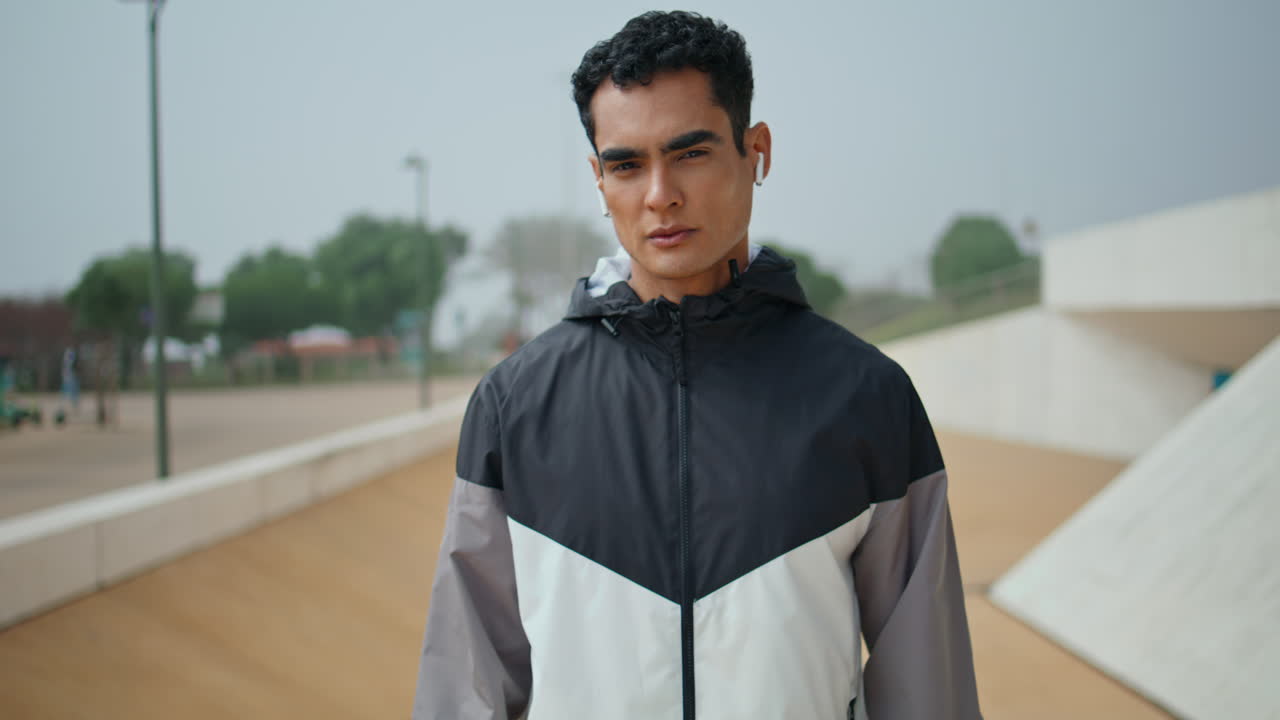 Man athlete zip jacket in urban park. Confident handsome sportsman look camera