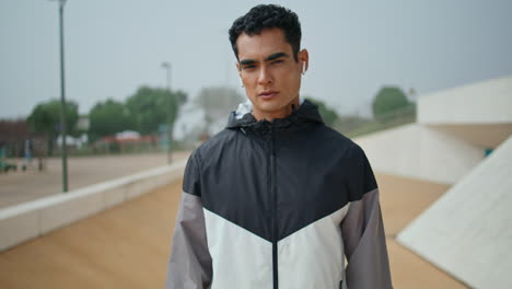 hombre atleta chaqueta con cremallera en el parque urbano. confiado guapo deportista mirada cámara