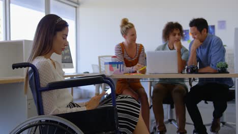 Seitenansicht-Einer-Jungen-Kaukasischen-Behinderten-Frau,-Die-An-Einem-Digitalen-Tablet-Gegen-Drei-Geschäftsleute-Arbeitet