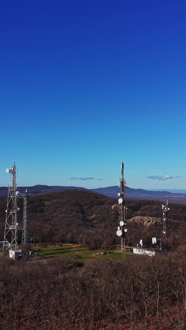 Unas torres de comunicación se alzan sobre una colina cerca de un océano azul bajo un cielo despejado
