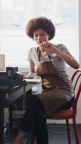 vertical video of biracial female worker drawing design of jewellery in slow motion