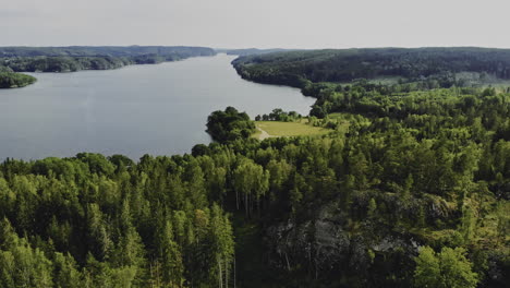 aerial shot of forested hills and large lake in sweden, forward motion