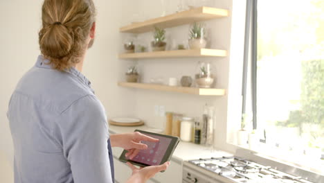 A-young-Caucasian-man-with-curly-hair-is-using-a-tablet-for-a-smartphone-app