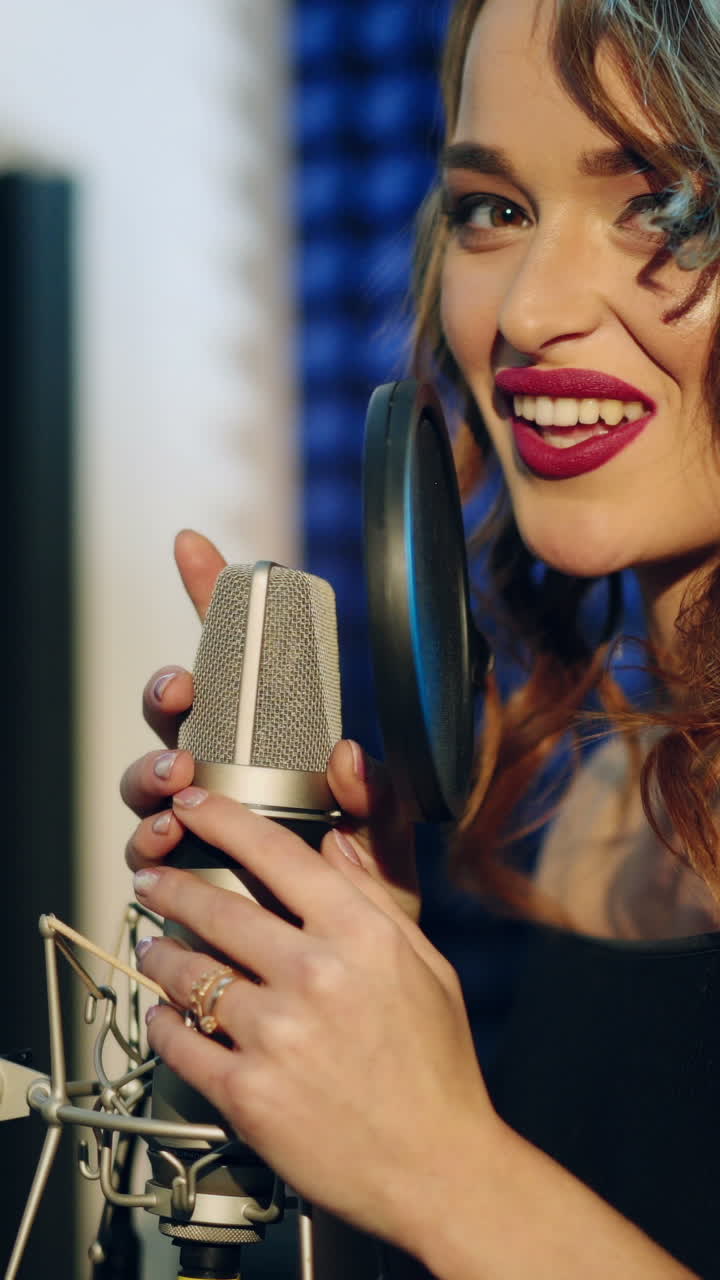 Vinnitsa, Ucraina - Maggio 2019: Giovane donna che registra una canzone in uno studio professionale. La ragazza canta nel microfono. Video verticale