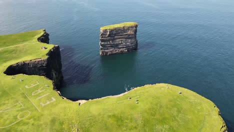 drone shot flying around downpatrick head from right to left showing the 64 eire sign