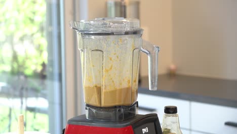 blending together all ingredients inside blender to make a almond butter orange juice sauce to pour over zucchini noodles