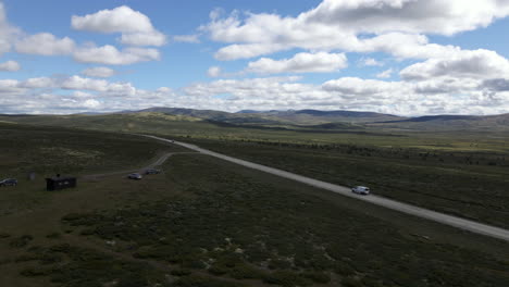 Drone-footage-shows-a-jeep-travelling-down-an-isolated-road-while-a-numerous-hills-are-visible-in-the-background