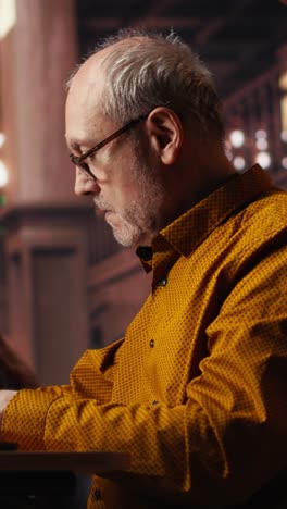 vertical video focused senior guy reading academic text on laptop at the university