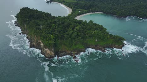 Baumbedecktes-Tropisches-Klippenküstengelände-Mit-Meereswellen,-Die-Manuel-Antonio-Beach,-Costa-Rica-4K-Drohne-Plätschern